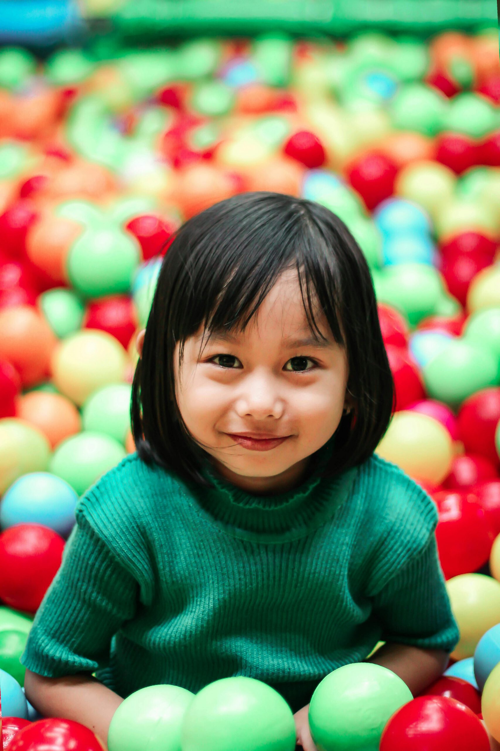 Adorable girl enjoying playtime in a vibrant indoor ball pit.
